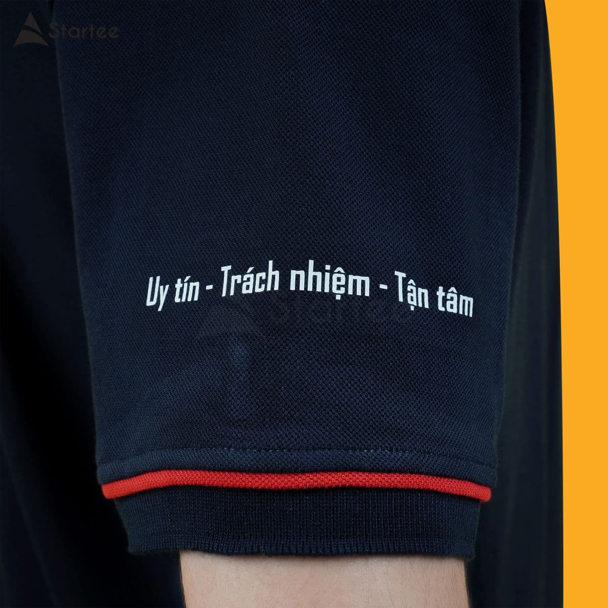 Khẩu hiệu in chữ nghiêng trên tay áo polo navy viền đỏ