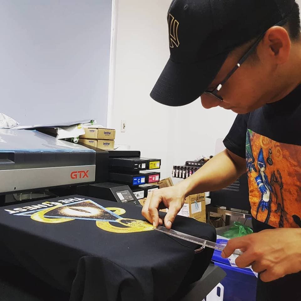 Brother GTX DTG printer jetting CMYK ink dots and a white ink layer onto a shirt